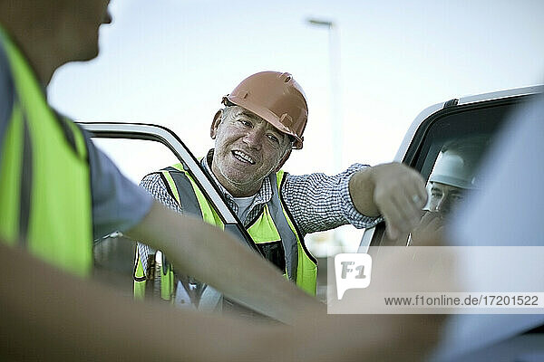 Three construction workers talking by car