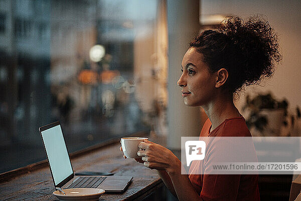 Frau mit Laptop  die in einem Café sitzt und Kaffee trinkt