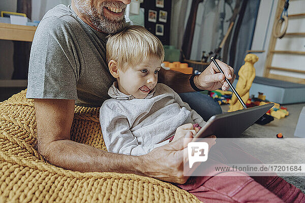 Father assisting son with E-learning on tablet at home