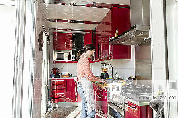 Junge Frau  die zu Hause in der Küche steht und Essen zubereitet