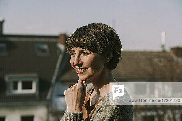 Beautiful smiling woman with hand on chin during sunny day
