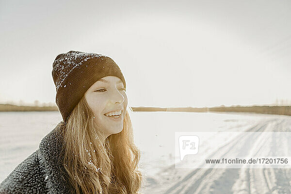 Porträt eines schönen Teenagers  der im Freien steht und gegen die aufgehende Wintersonne lächelt