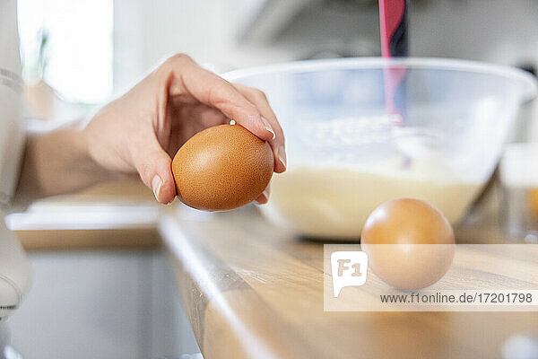 Frau schlägt Eier in der Küche auf