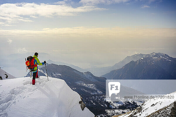 Männlicher Bergsteiger bewundert die Aussicht  während er auf einem schneebedeckten Berg steht