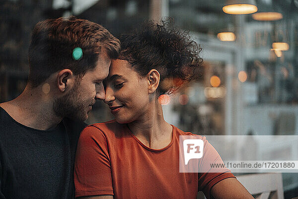 Romantisches Paar mit geschlossenen Augen sitzt sich im Café gegenüber