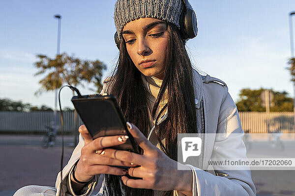 Jugendliches Mädchen hört Musik über Kopfhörer und schaut auf ihr Handy  Sevilla  Spanien