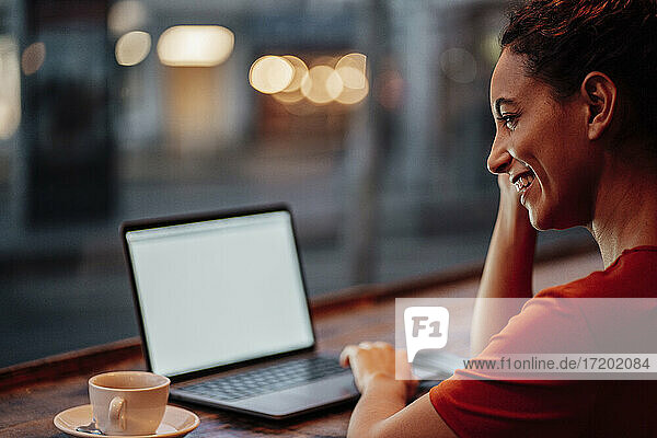 Lächelnde Frau  die einen Laptop benutzt  während sie in einem Café sitzt