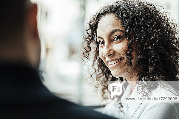 Lächelnde Geschäftsfrau  die einen Kollegen ansieht  während sie im Cafe sitzt