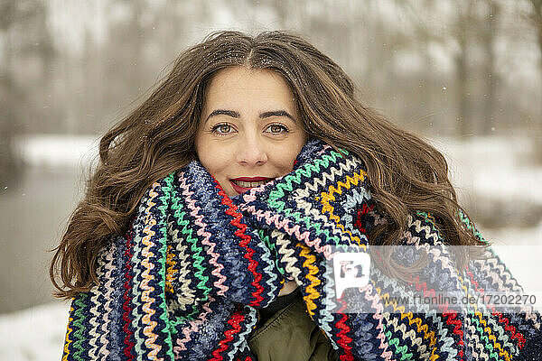 Smiling beautiful woman wrapped in multi colored blanket during winter