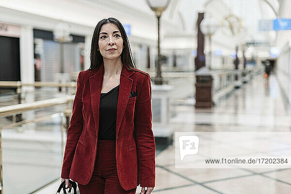 Selbstbewusste reife Geschäftsfrau in rotem Blazer beim Gehen in der U-Bahn-Station