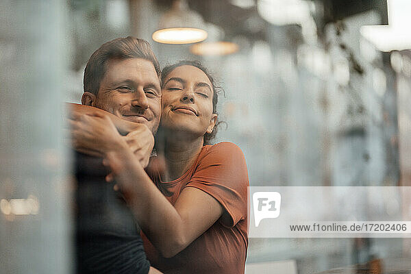 Junge Frau umarmt Mann  während sie in einem Café sitzt