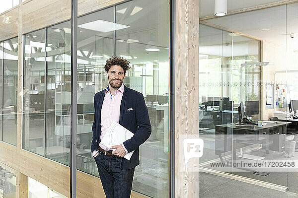 Male entrepreneur with document against glass wall at office