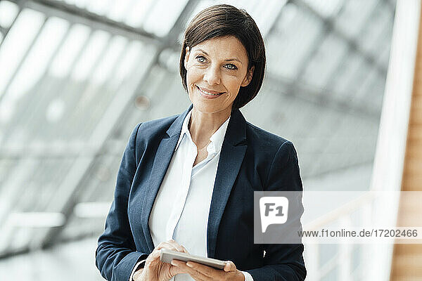 Lächelnde Geschäftsfrau mit digitalem Tablet im Korridor