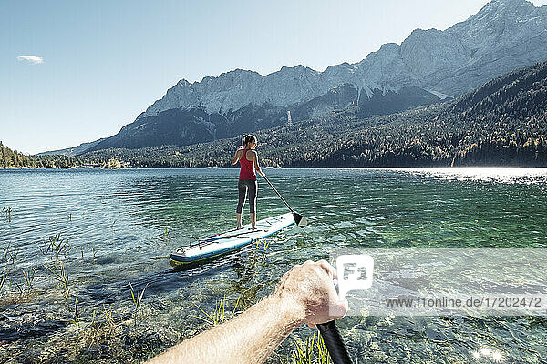 Germany  Bavaria  Garmisch Partenkirchen  Young couple stand up padling on Lake Eibsee  overlooking Zugspitze Mountain