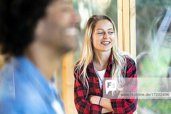 Lächelnde Frau schaut weg  während sie mit einem Mann im Vorgarten steht