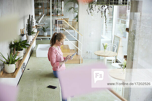 Frau benutzt digitales Tablet  während sie sich zu Hause auf die Arbeitsplatte stützt
