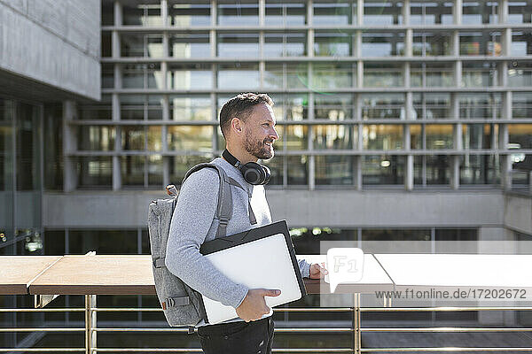 Lächelnde reife männliche Fachkraft  die Akten hält  während sie vor einem Gebäude steht