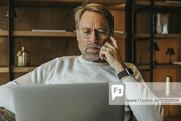 Älterer Mann mit Brille am Laptop