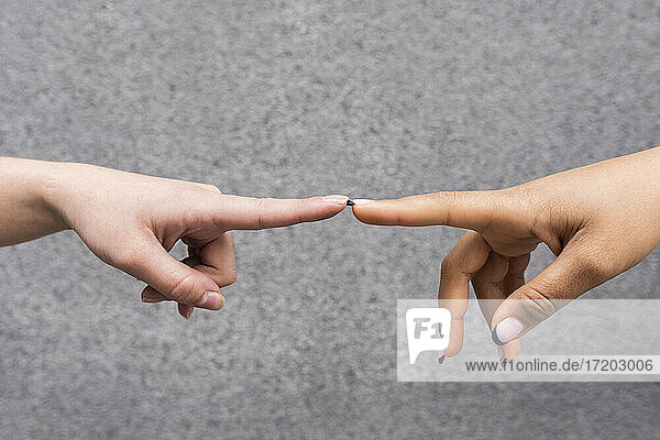Hände von zwei jungen Frauen  die sich mit den Zeigefingern berühren