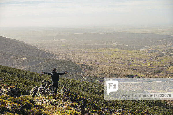 Man with arms outstretched looking at view while standing on rock at Somosierra  Madrid  Spain