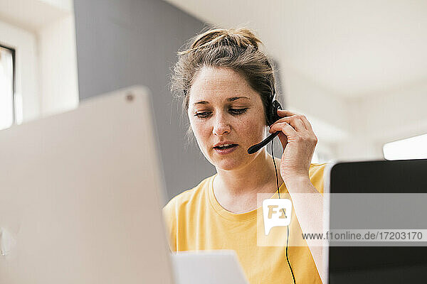 Businesswoman discussing through headphones while working at home