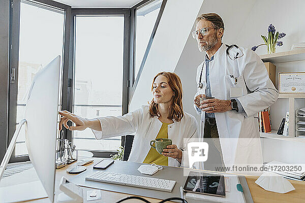 Ärzte trinken Kaffee  während sie in der Klinik am Computer arbeiten
