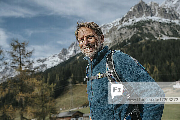 Lächelnder reifer Mann mit Rucksack vor dem Himmel am Hochkonig  Salzburger Land  Österreich