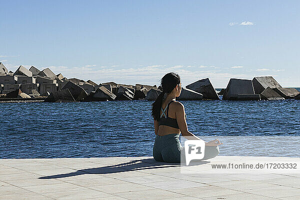 Junge Frau meditiert auf der Promenade an einem sonnigen Tag