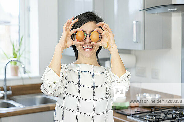 Happy woman in the kitchen playing with eggs