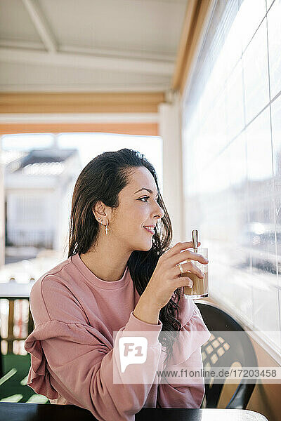 Schöne Frau mit Tasse schaut durch das Fenster in einem Café