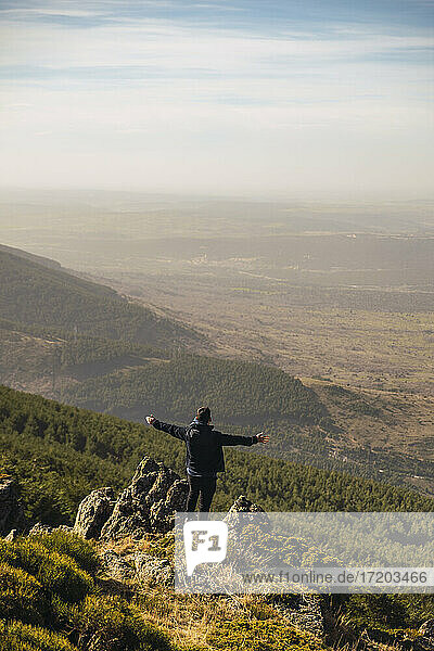 Male tourist with arms outstretched standing on rock during vacations at Somosierra  Madrid  Spain
