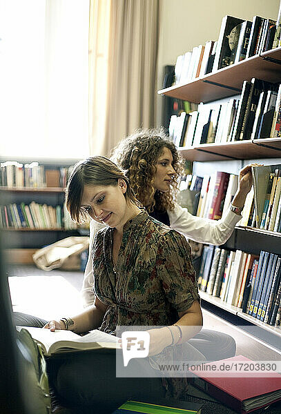 Studentinnen lesen Bücher  während sie in der Bibliothek sitzen