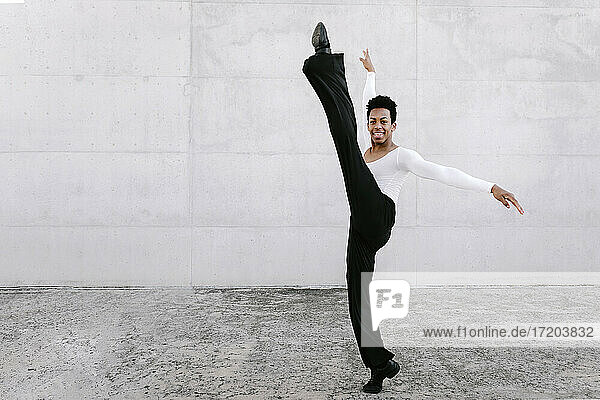 Flexibler männlicher Tänzer beim Üben an der Wand