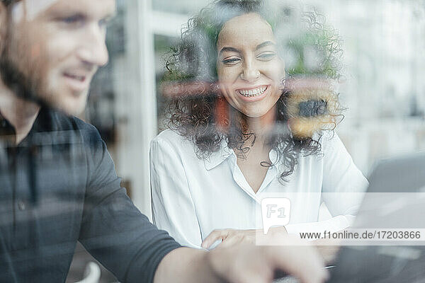 Geschäftsfrau lächelt bei der Arbeit mit einem Kollegen in einem Cafe