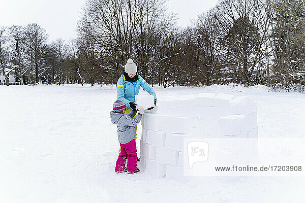 Mutter und Tochter bauen ein Iglu im Park