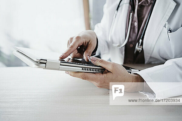 Ärztin mit digitalem Tablet am Schreibtisch im Krankenhaus