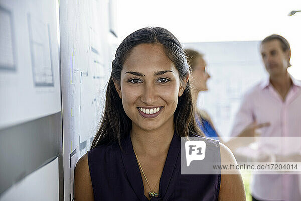 Smiling female architect standing by white board in office