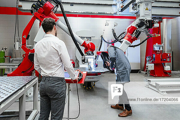 Men examining at robotics in factory