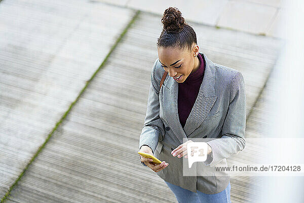 Geschäftsfrau benutzt Mobiltelefon  während sie auf dem Gehweg steht
