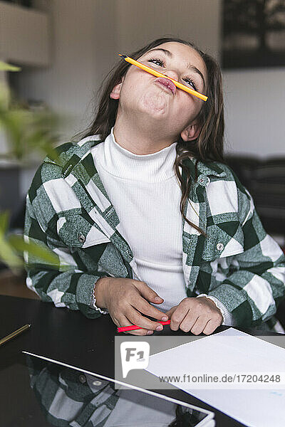 Mädchen spielt mit Bleistift am Tisch