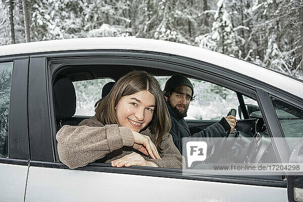 Smiling woman looking out of window while sitting with man in car