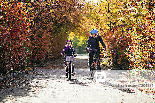 Fröhliche Mutter und Tochter beim Radfahren im Herbst im Park
