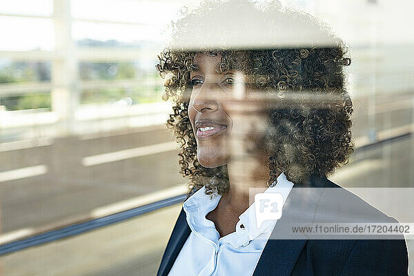 Weibliche Unternehmerin schaut durch ein Fenster  während sie in einem modernen Büro steht