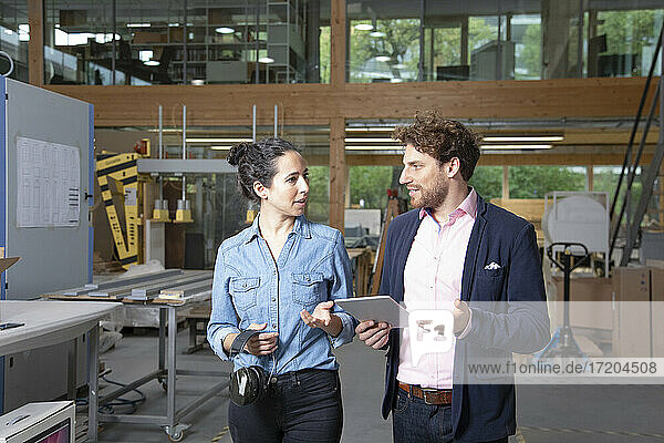 Businessman and businesswoman discussing strategy in factory