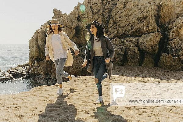 Lächelnde Schwestern laufen auf Sand am Strand