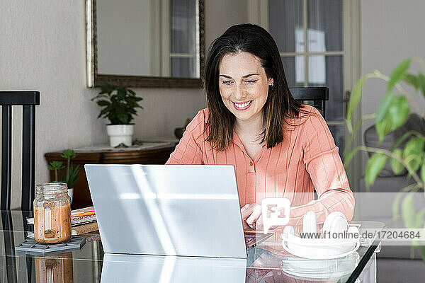 Smiling businesswoman working on laptop at home office