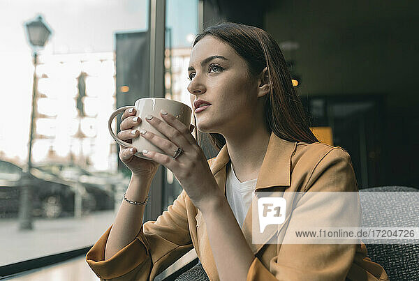 Schöne Frau trinkt Kaffee und schaut durch das Fenster eines Cafés