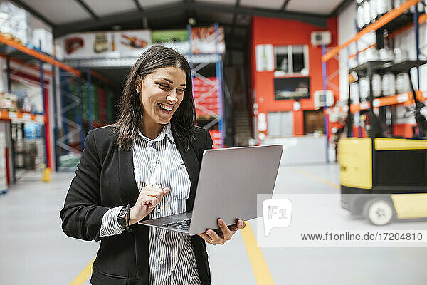 Lächelnde Managerin mit Laptop in einem beleuchteten Vertriebslager