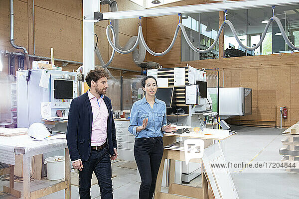 Male and female entrepreneurs discussing while walking in factory