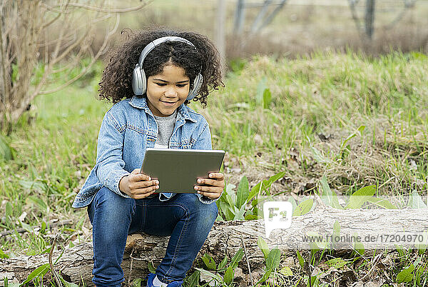 Boy wearing headphones using digital tablet in nature